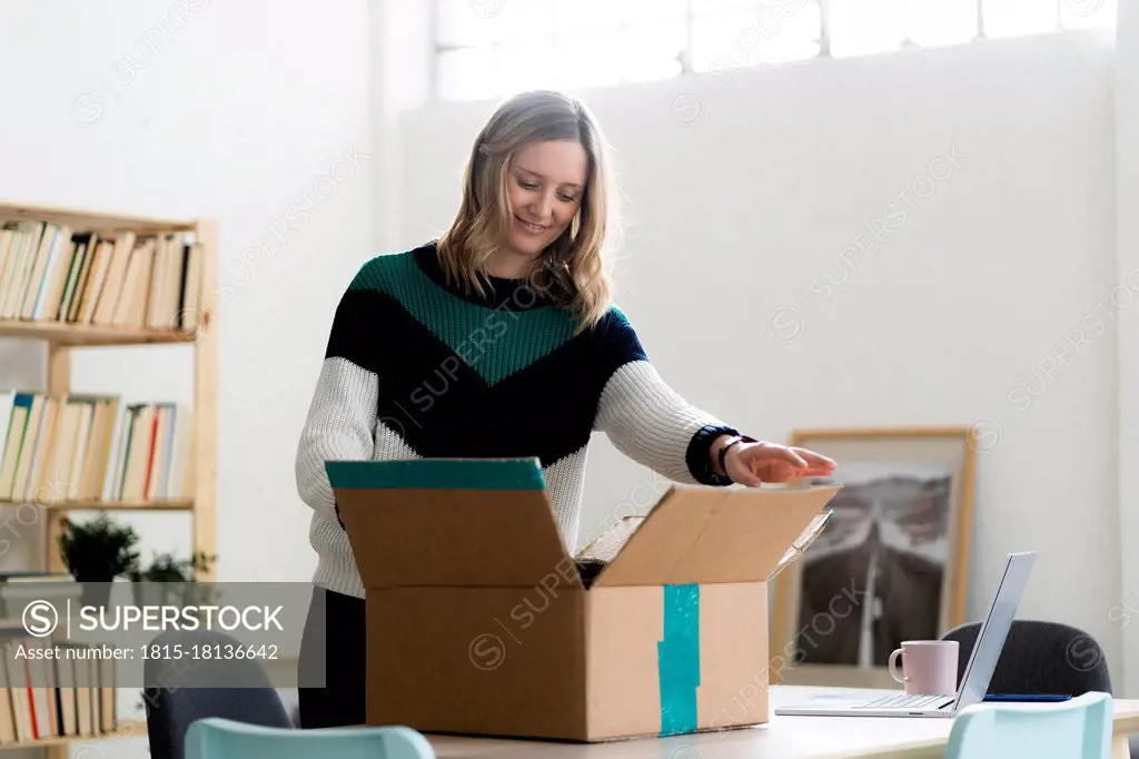 Mid adult woman opening cardboard box at home