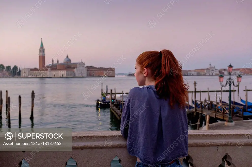 Woman looking at view while standing in city at sunset during vacations