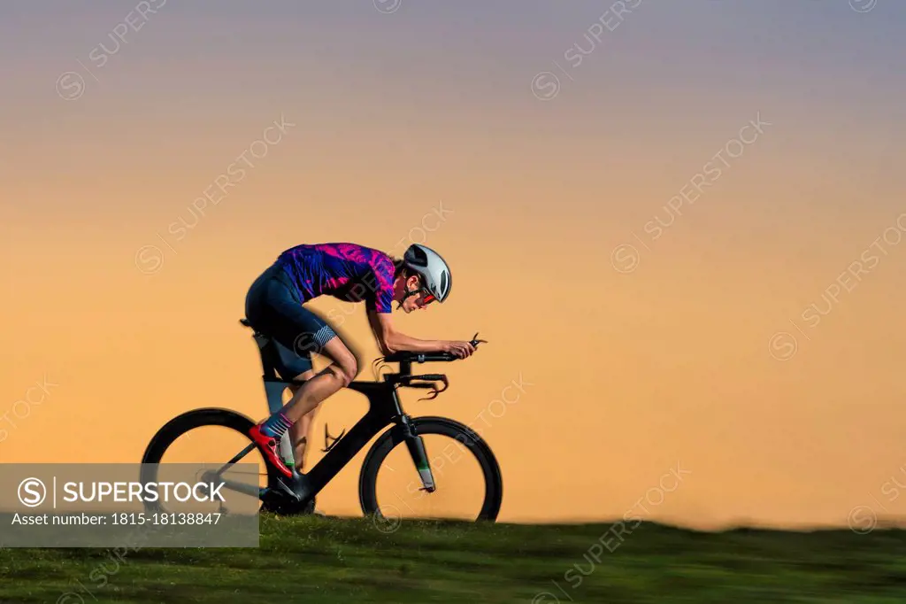 Male sportsperson triathlon riding bicycle on land during sunset