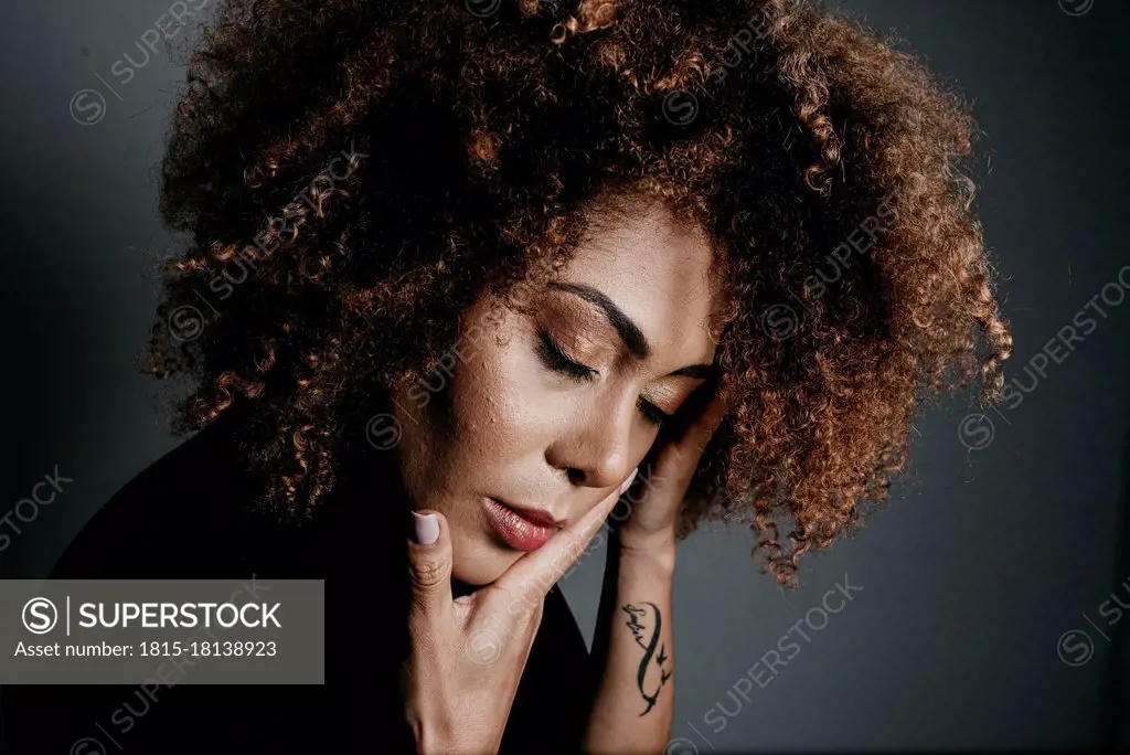 Young beautiful woman with eyes closed on grey background