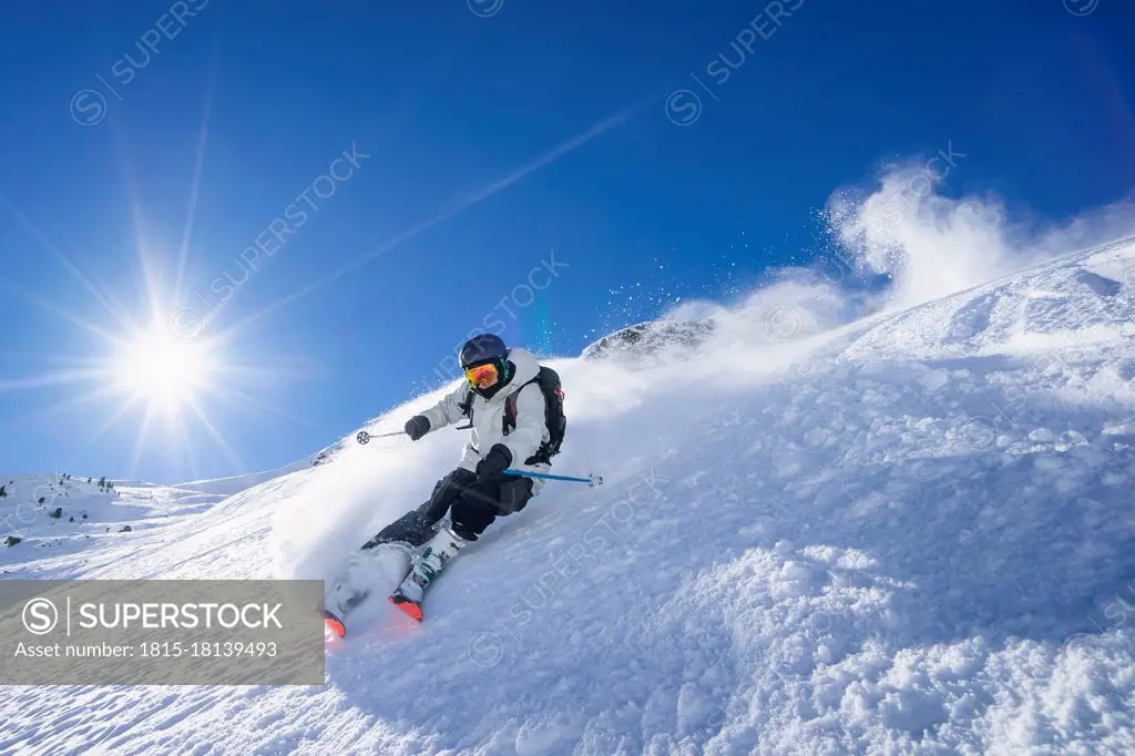 Sun shining over young man skiing in¶ÿArlberg¶ÿmassif
