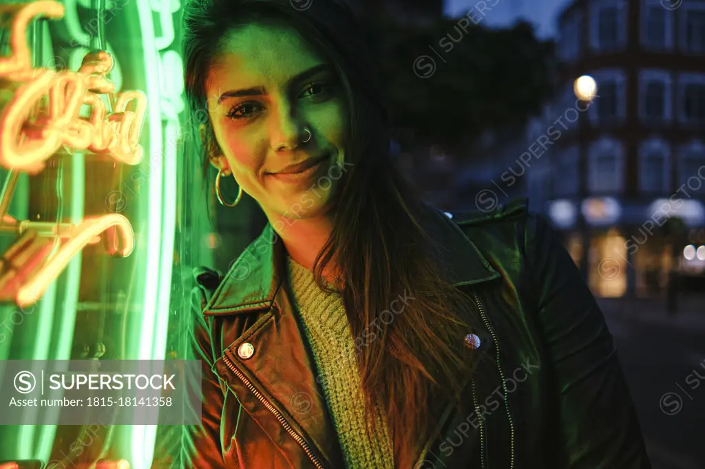 Beautiful woman with jacket standing by illuminated light