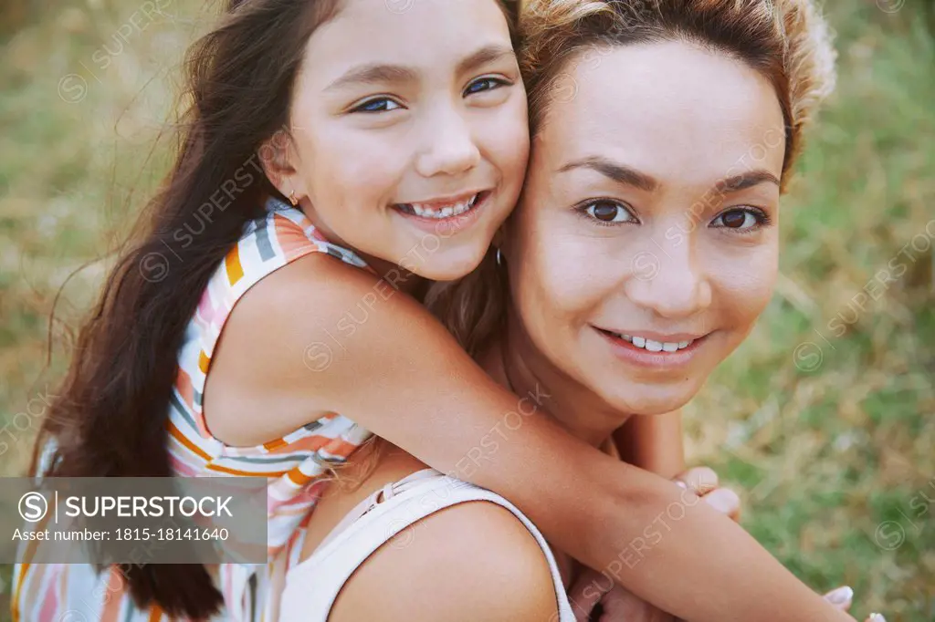Smiling mother giving piggyback ride to daughter