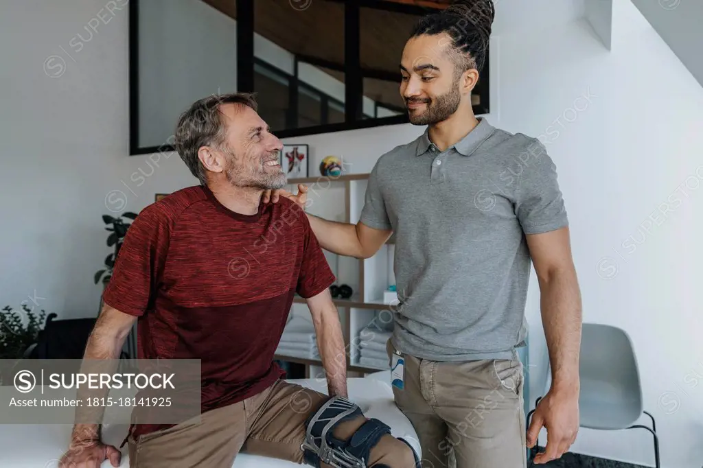 Male physiotherapist with smiling patient in medical practice