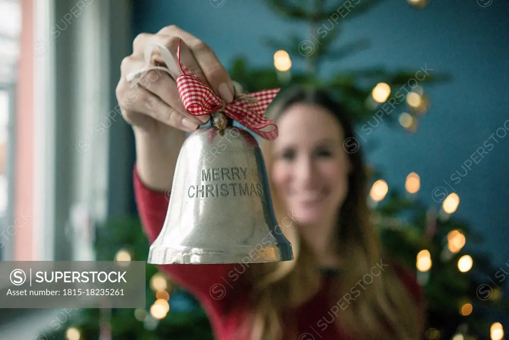 Woman's hand holding silver Christmas bell
