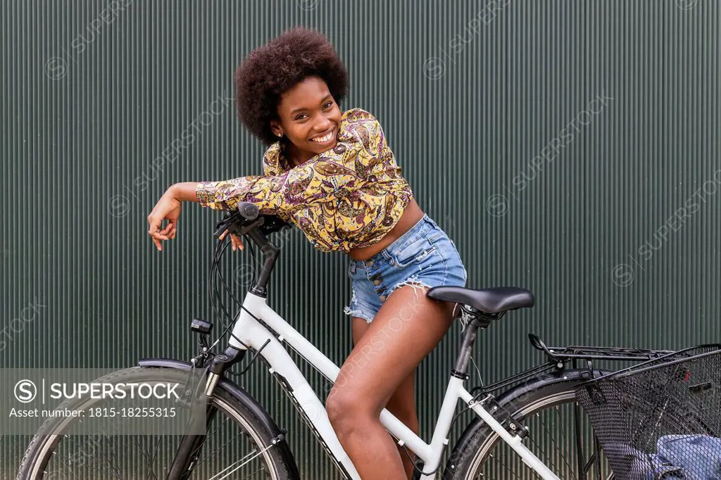 Beautiful woman leaning on bicycle by wall