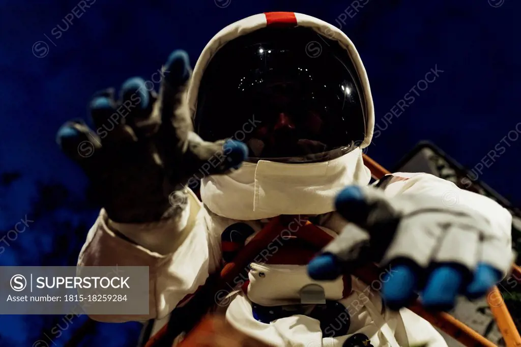 Young female astronaut in space suit gesturing at night