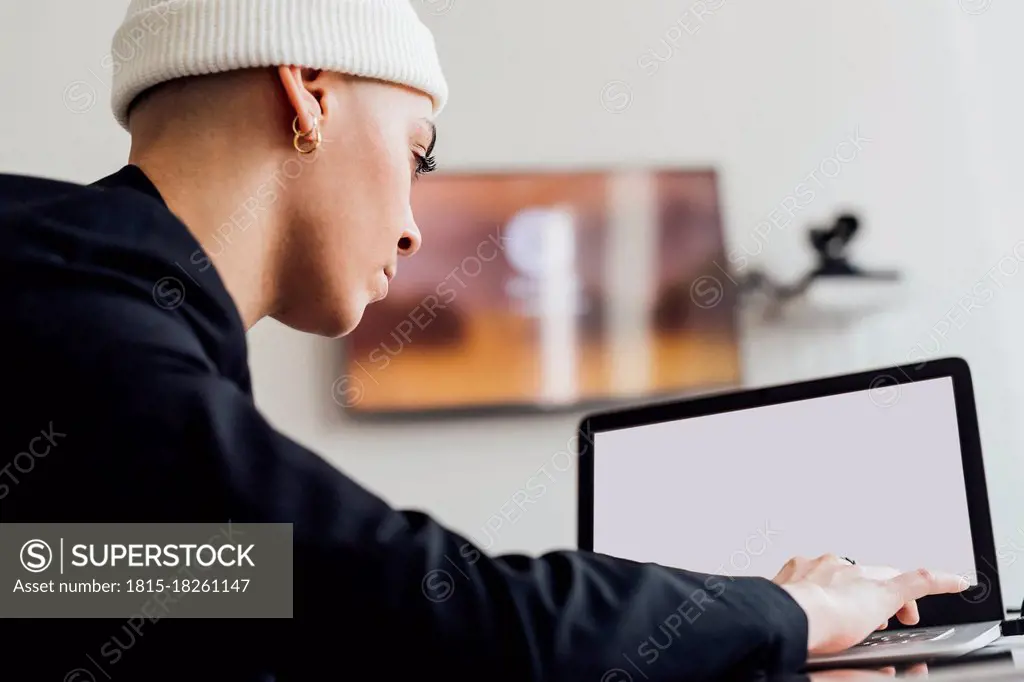 Female entrepreneur with knit hat using laptop in office