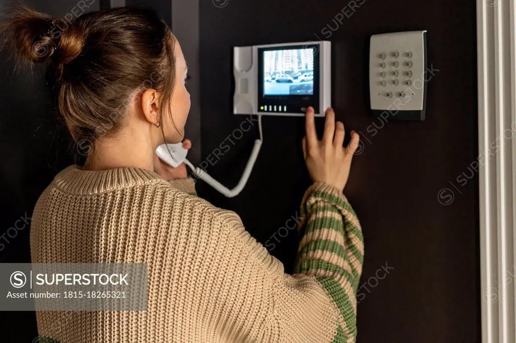Woman using intercom device at home