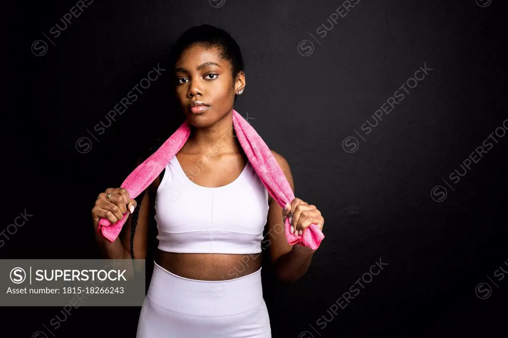 Young woman with towel standing against black background