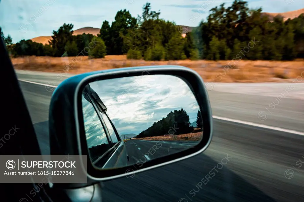 Side-view mirror reflection of car driving along State Highway 8