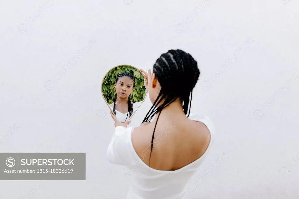 Braided hair woman looking at reflection in mirror