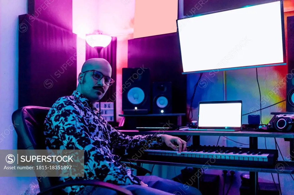 Male music composer sitting by piano in studio