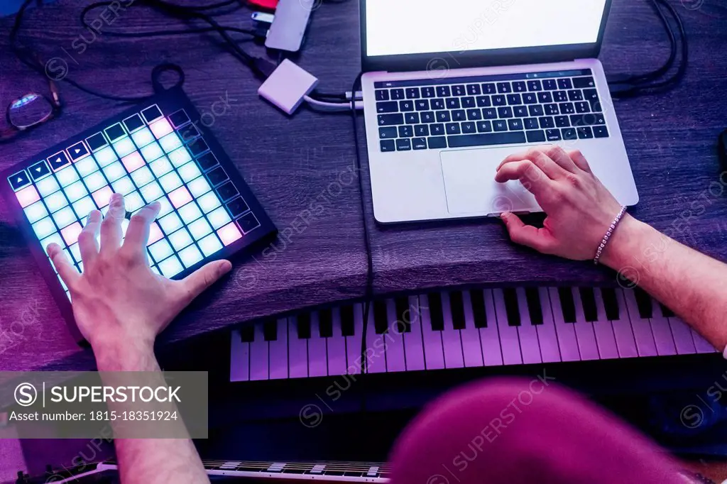 Man using digital tablet and laptop while composing music at studio