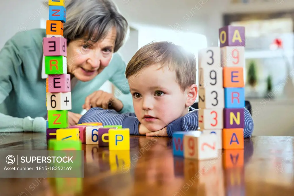 Senior woman and boy looking at toy block stack on table