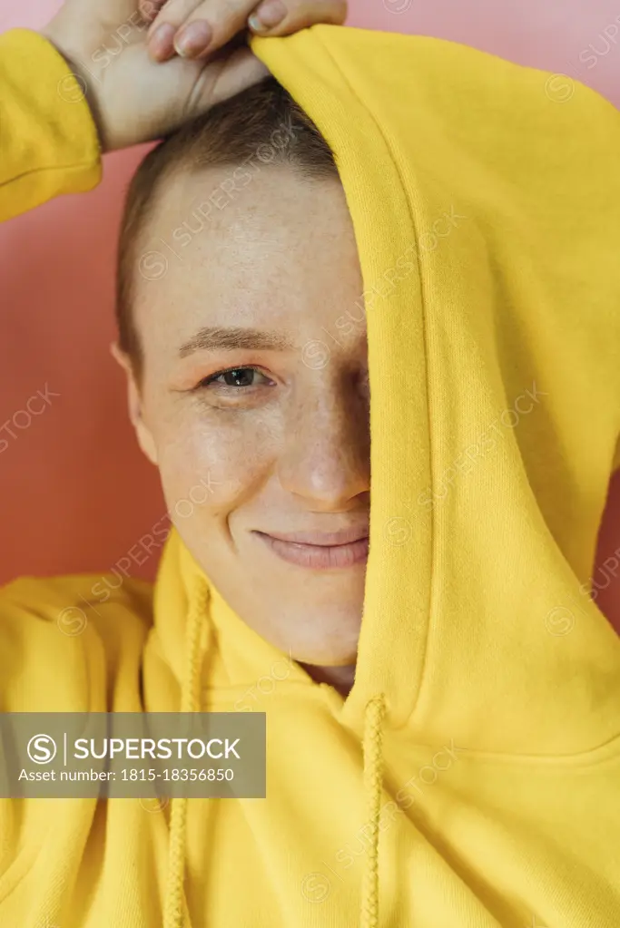 Young woman covering half face with hoodie in studio