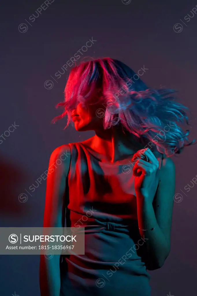 Young woman tossing hair against colored background
