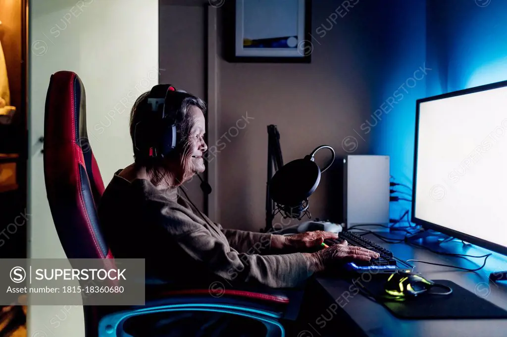 Senior woman wearing headphones using computer while sitting at table