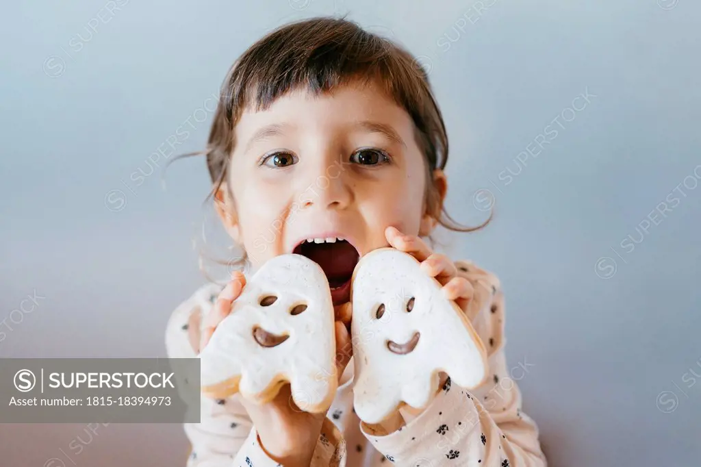 Mischievous little girl with mouth open showing ghost cookies