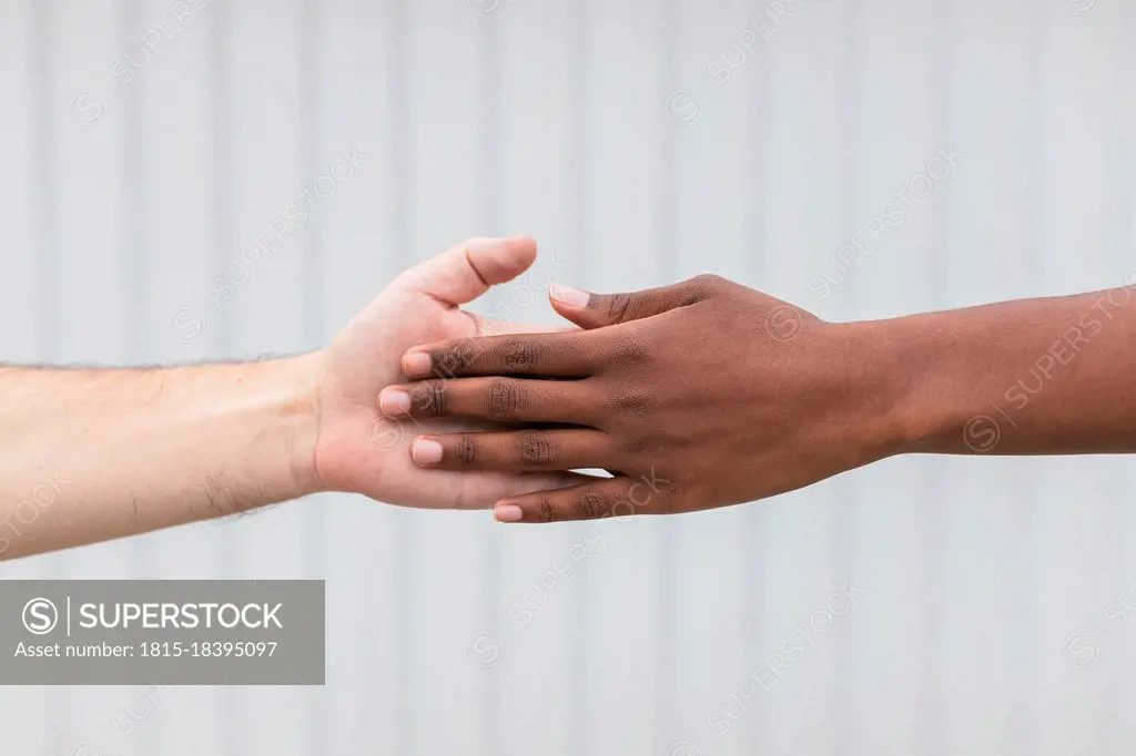 Woman and man touching hands by white wall