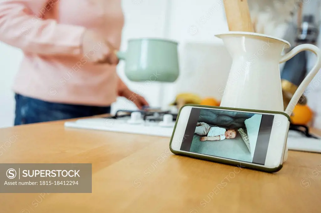 Woman preparing food during video call through mobile phone at kitchen
