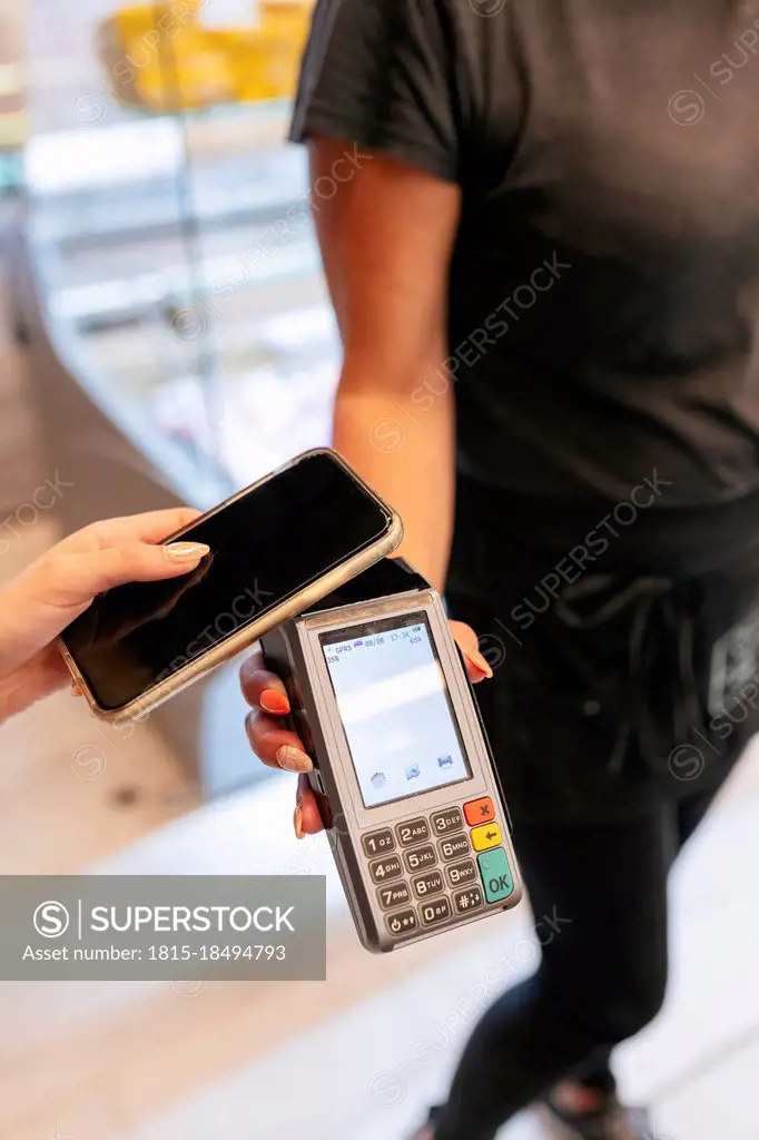 Woman paying online through mobile phone to waitress at food court