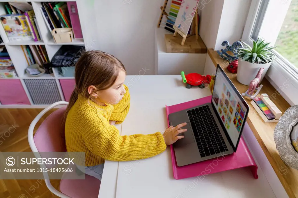 Girl using laptop on desk while learning at home
