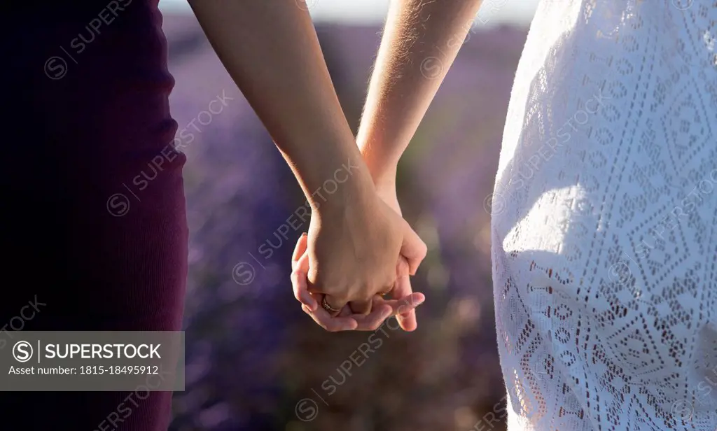 Female friends holding hands on field
