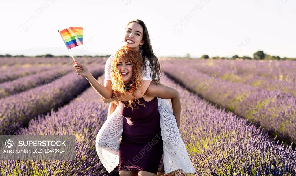 Happy girlfriends with LGBTQIA Flag in lavender field