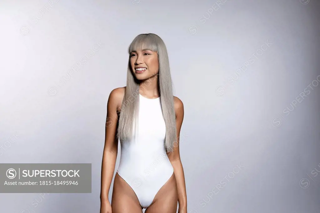 Beautiful young woman in bodysuit standing against white background