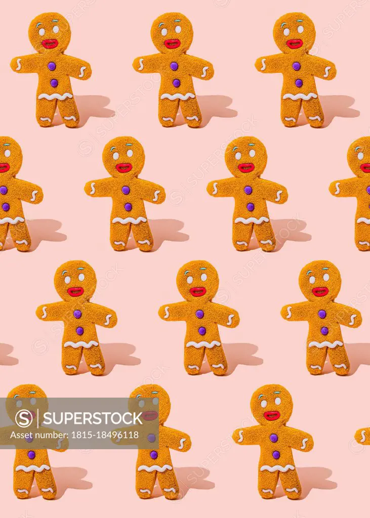 Pattern of gingerbread cookies flat laid against pink background