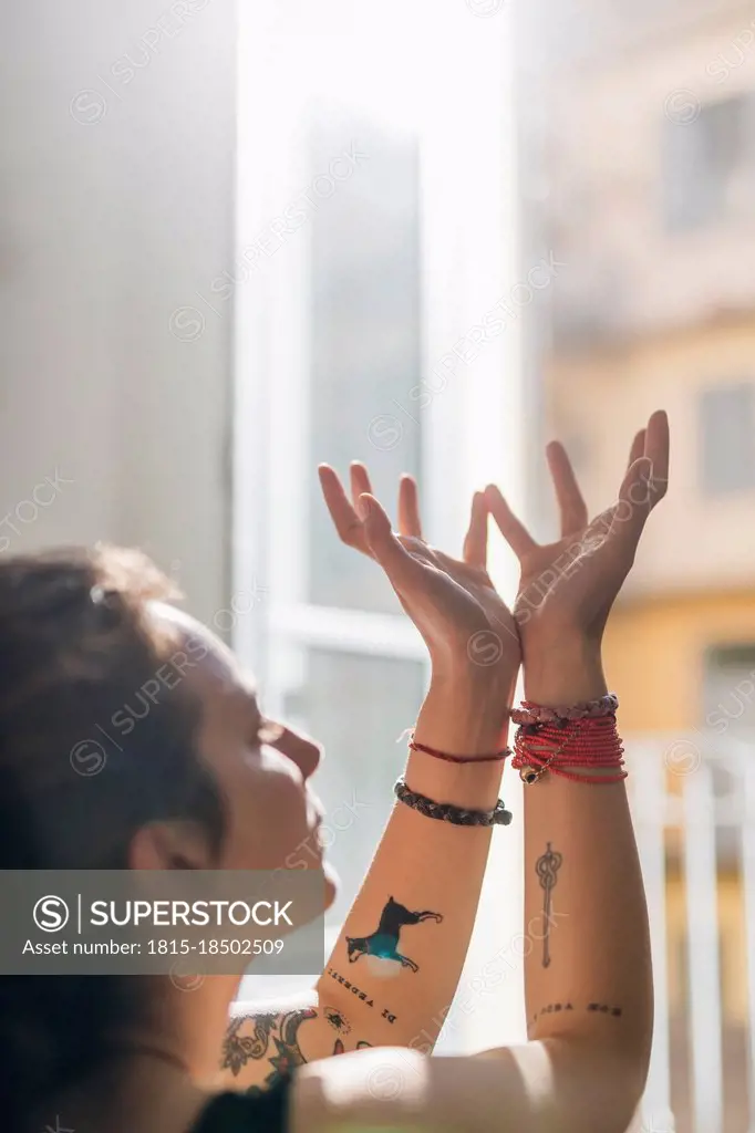 Woman with hands raised meditating at home