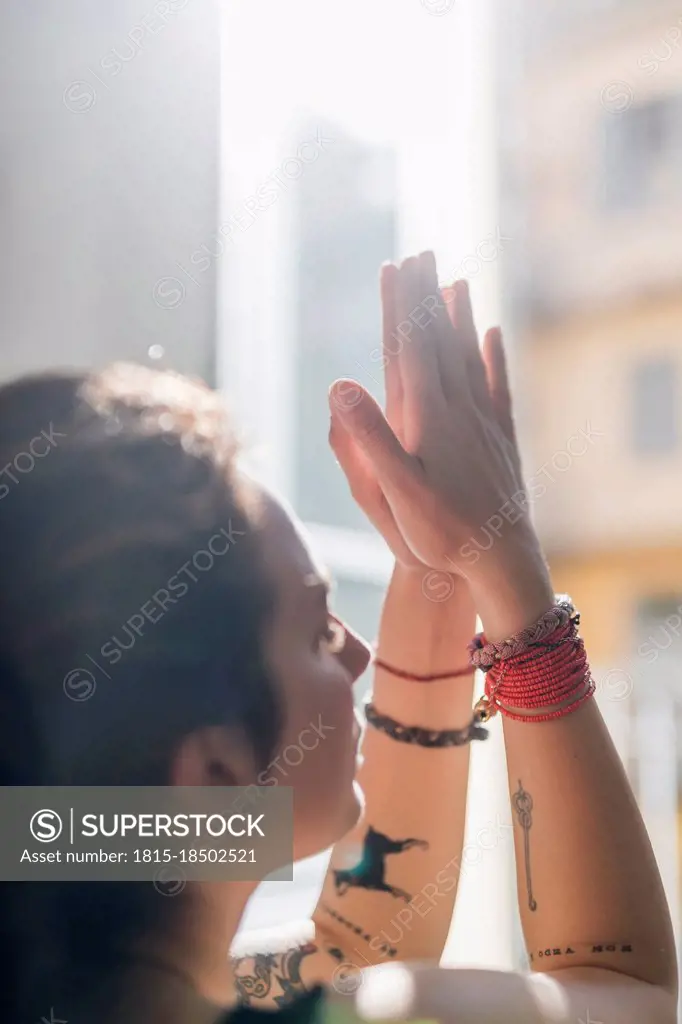 Woman with hands clasped practicing yoga in apartment