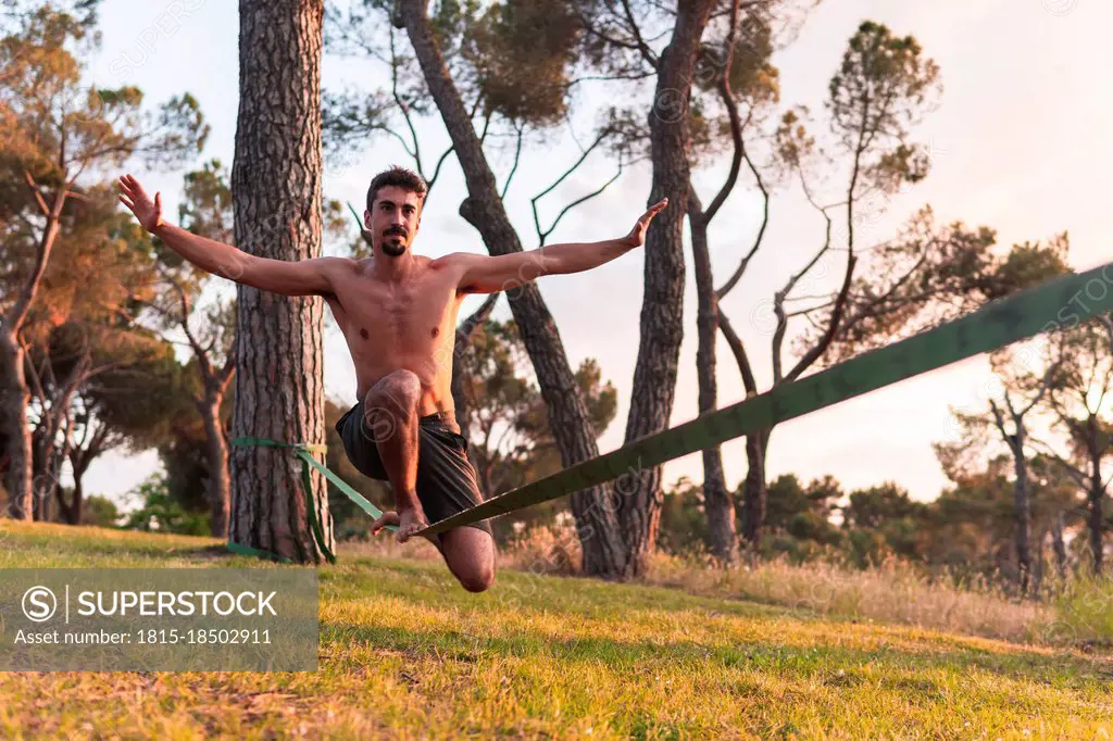 Man with arms outstretched doing slacklining during sunset