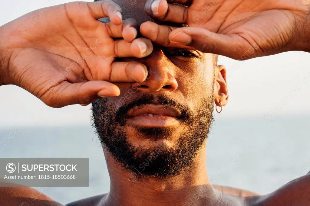 Mid adult man covering eye with hand
