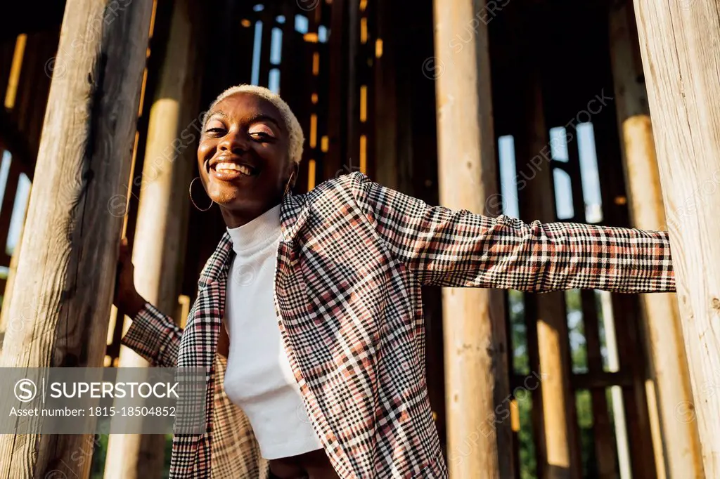 Smiling woman standing amidst wooden poles
