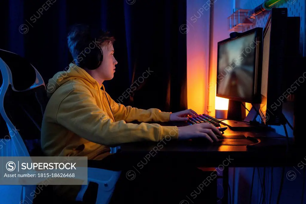 Boy playing game on desktop PC on table at home
