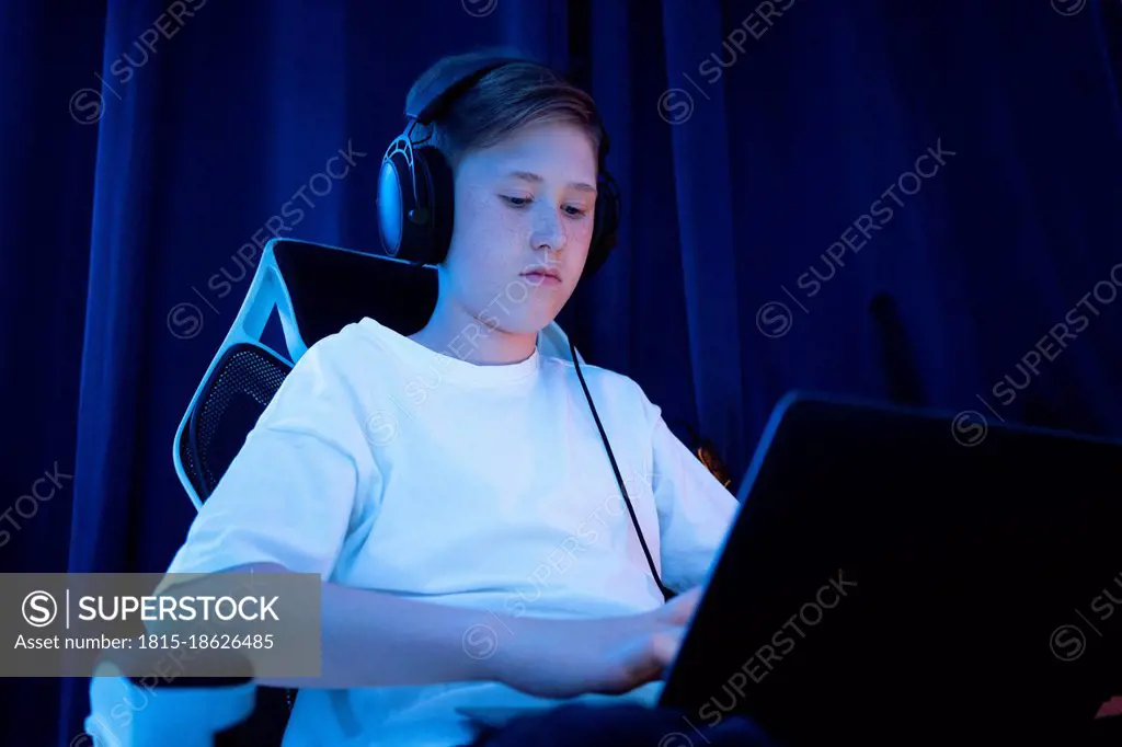 Boy with headphones using laptop at home
