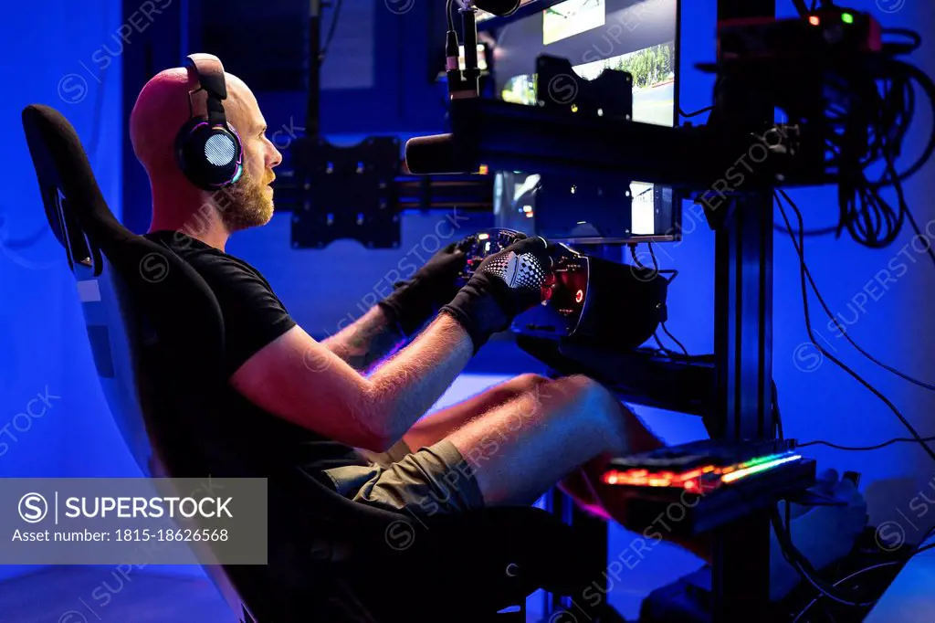 Male gamer wearing headphones while playing video game at studio