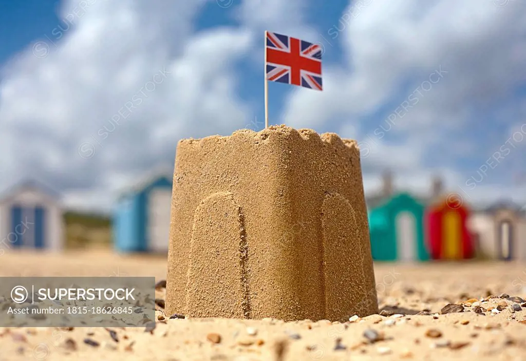 Sandcastle with Union Jack flag on beach during sunny day
