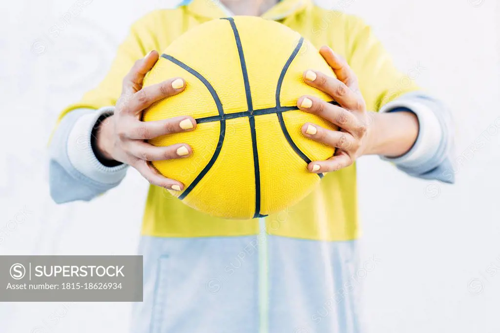 Young woman holding yellow basketball