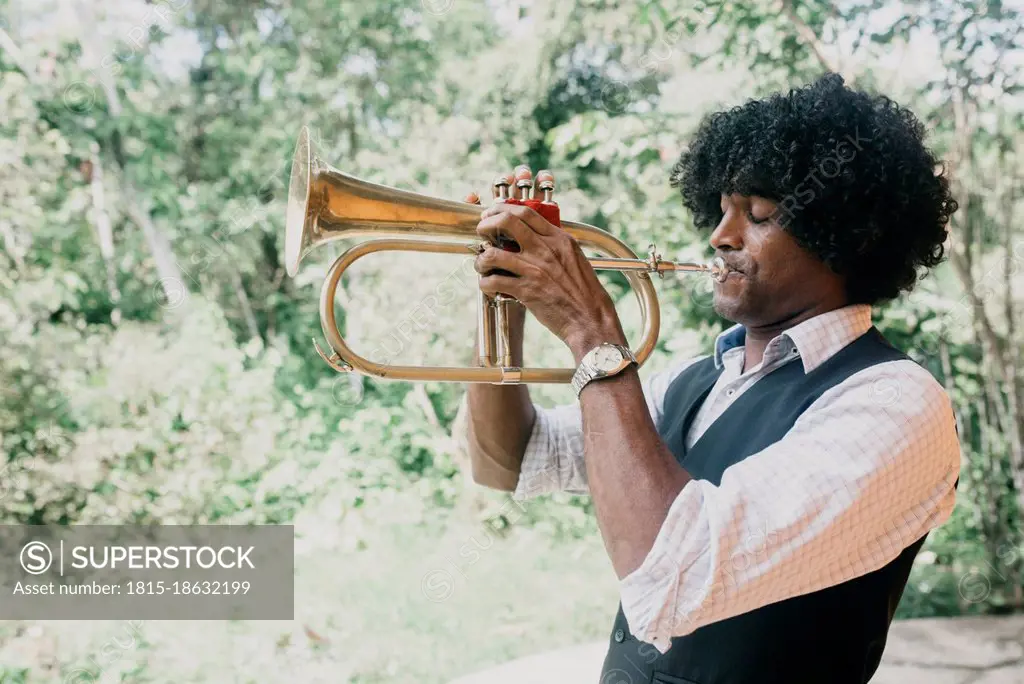 Man with curly black hair practicing trumpet