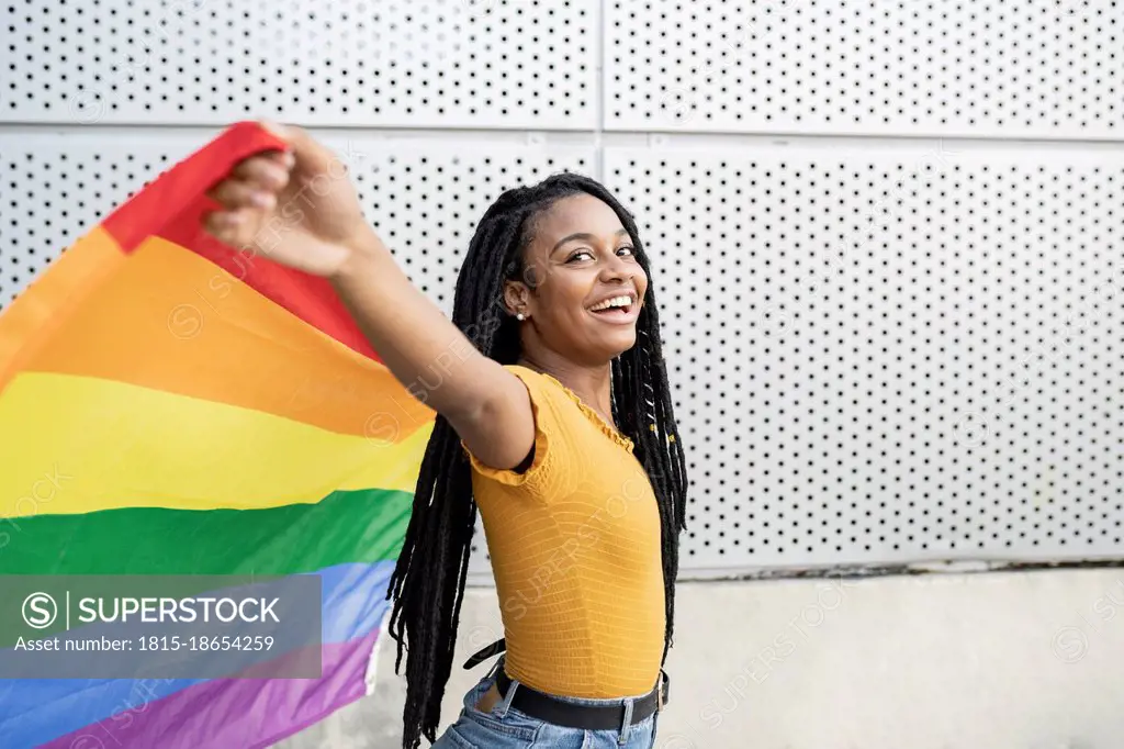 Happy lesbian woman with arms outstretched holding rainbow flag