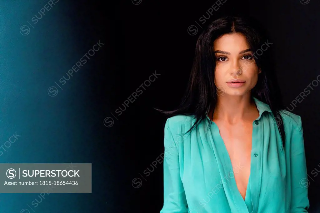 Beautiful young woman with black hair against black background