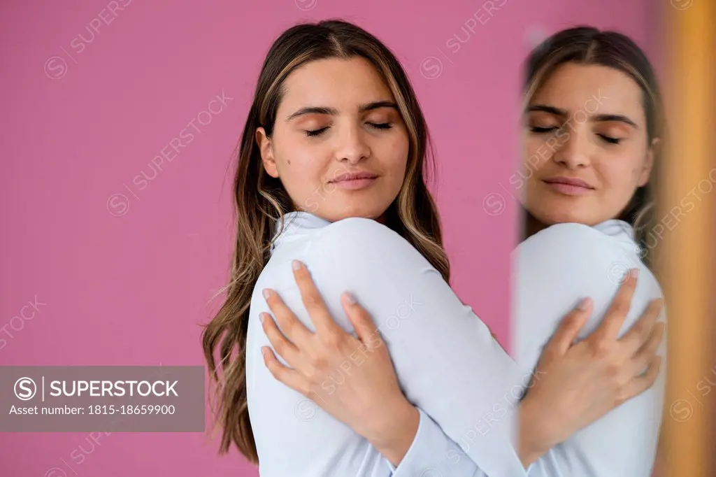 Businesswoman hugging herself by pink wall