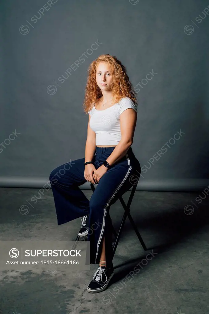 Blond young woman sitting on chair in studio