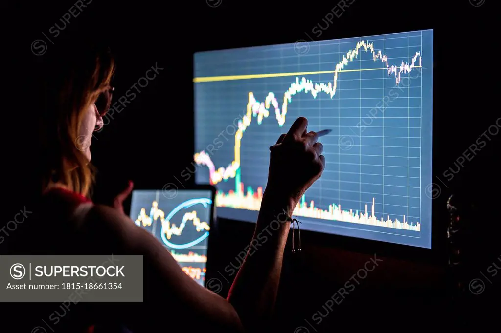 Businesswoman checking stock market data on screen in office