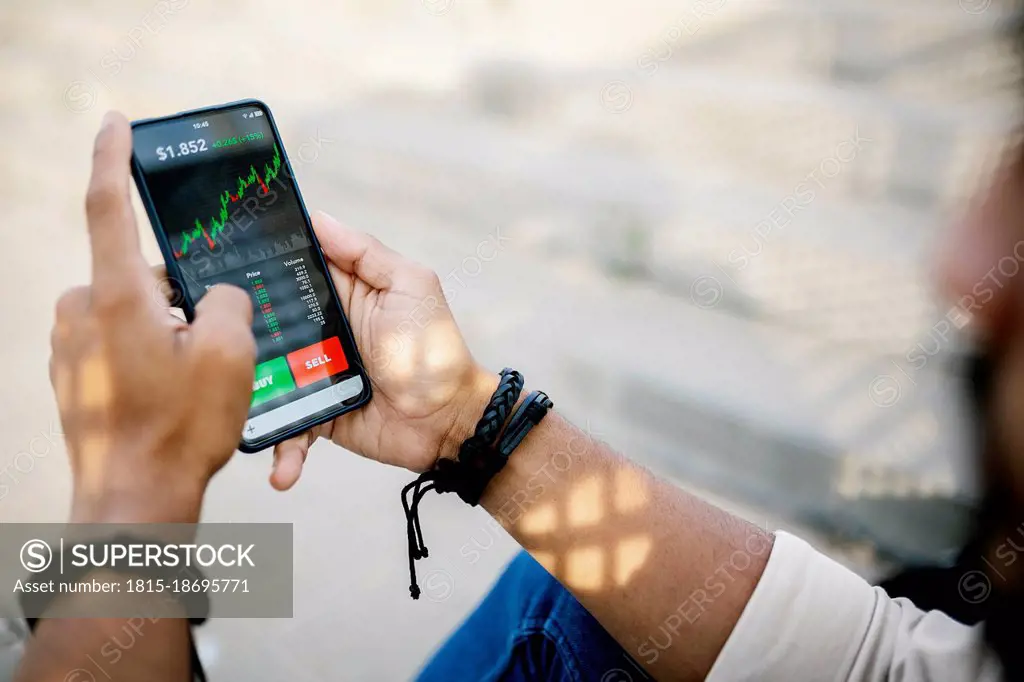 Man checking stock market graph through mobile phone