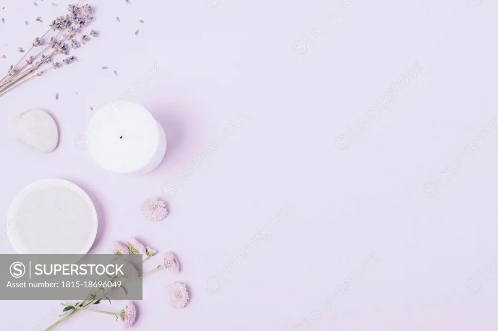 Bowl of cosmetic clay near lavender flowers with stone and candle