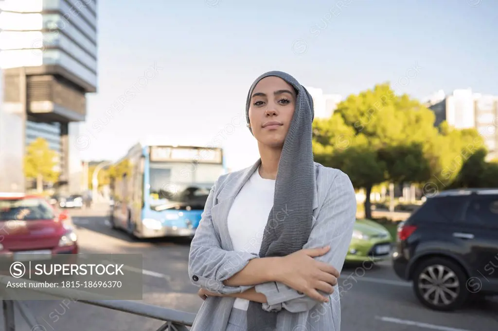 Confident woman standing with arms crossed on street